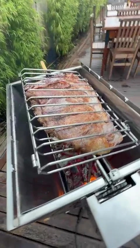 Grade com costela sobre o fogo na Churrasqueira Luxo, em um deck de madeira